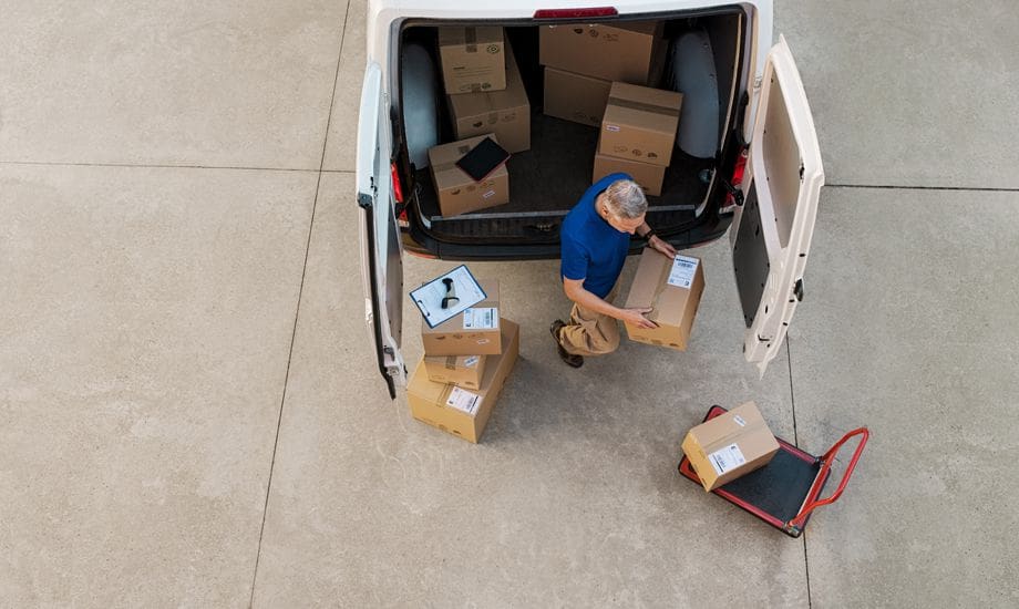 supply chain finance - logistics worker loading packages into a commercial vehicle